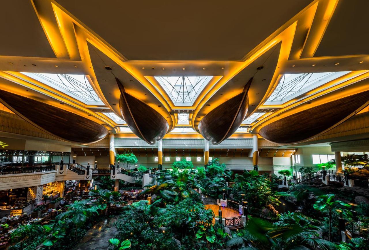 Grand Hyatt Dubai Hotel Ngoại thất bức ảnh The photo depicts the interior of a grand building, likely a hotel or resort, featuring a stunning atrium. The space is characterized by large, elegantly designed boat-shaped structures suspended from the ceiling, which are illuminated by warm light.