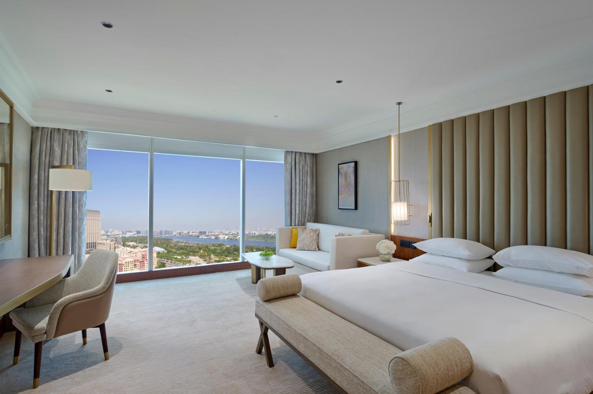 Grand Hyatt Dubai Hotel Ngoại thất bức ảnh The photo shows a modern hotel room featuring large windows with a view. The room is designed with a neutral color palette and elegant furnishings. There are two beds neatly made, a sofa area, and a small table. Soft lighting fixtures are present, an
