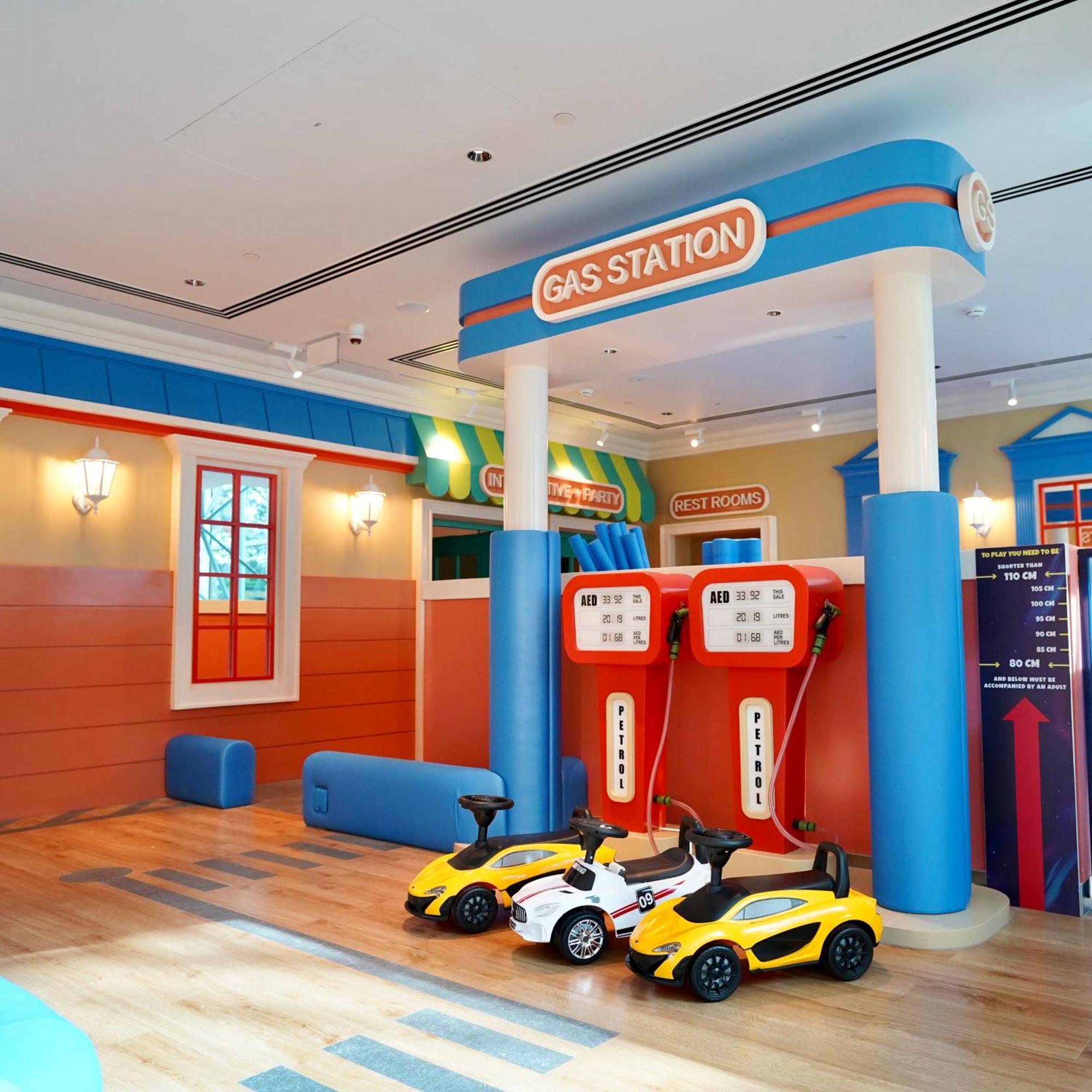 Grand Hyatt Dubai Hotel Ngoại thất bức ảnh The photo shows a brightly colored play area designed to resemble a gas station. There are two large gas pumps with a "GAS STATION" sign above them, set against a cheerful backdrop. The walls are painted in vibrant colors, with features like windows 