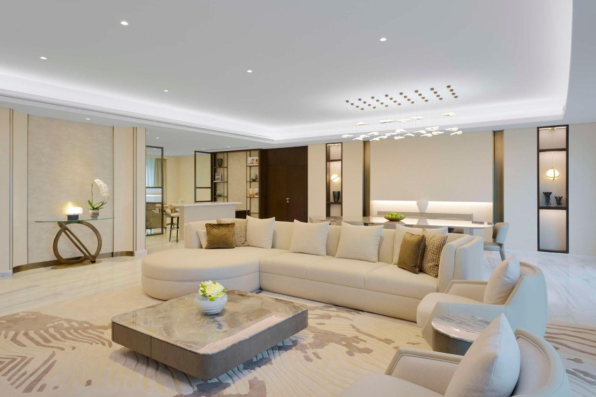 Grand Hyatt Dubai Hotel Ngoại thất bức ảnh The photo depicts a modern and luxurious living room. A large, L-shaped, light-colored sectional sofa occupies a central position, adorned with a few decorative pillows. In front of the sofa is a stylish coffee table that features a smooth surface, p