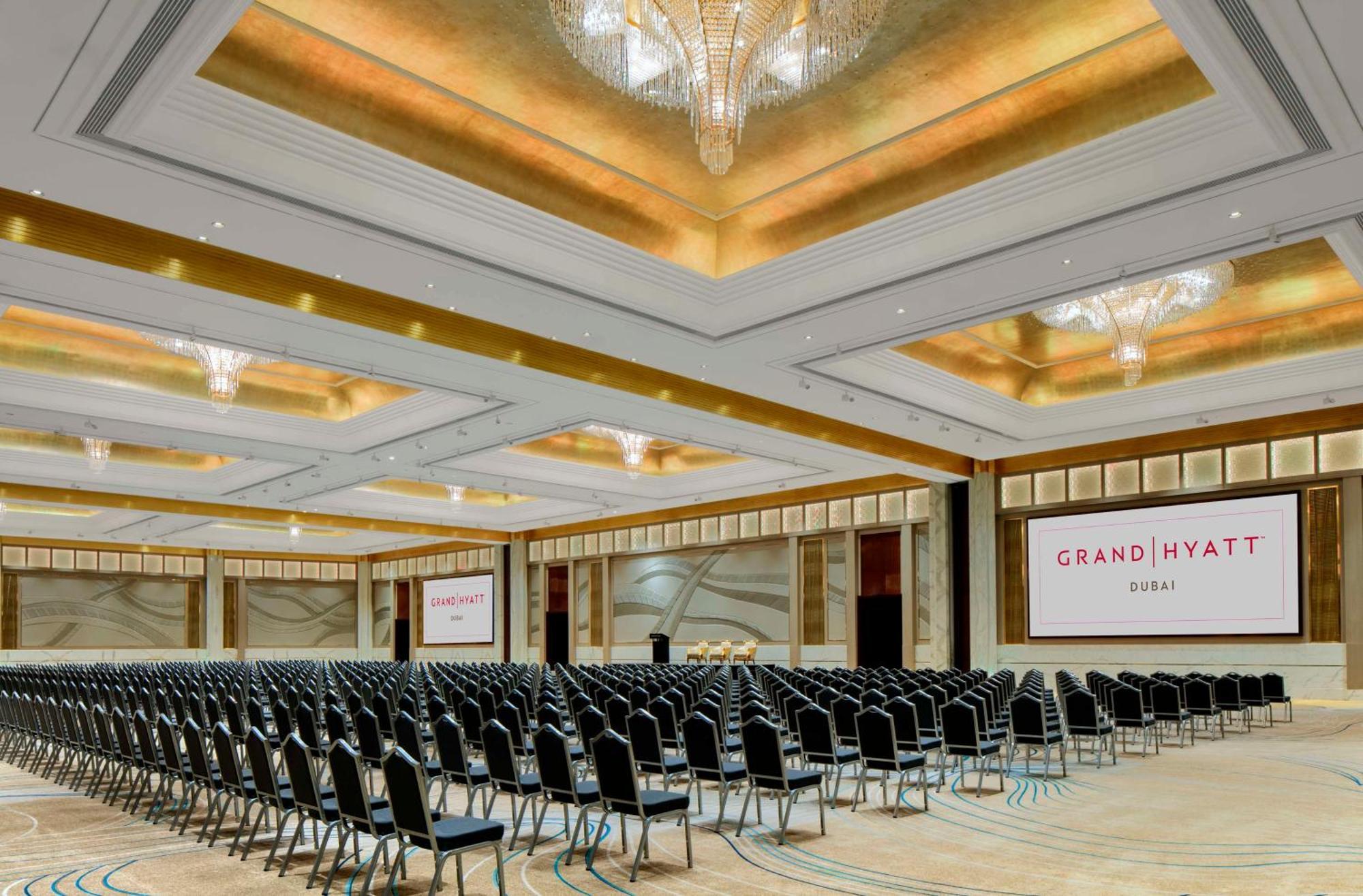 Grand Hyatt Dubai Hotel Ngoại thất bức ảnh The photo shows a large, elegantly designed conference room at the Grand Hyatt hotel. The room features rows of black chairs arranged for an event, indicating it is set up for an audience. The ceiling has a decorative design with chandeliers that pro