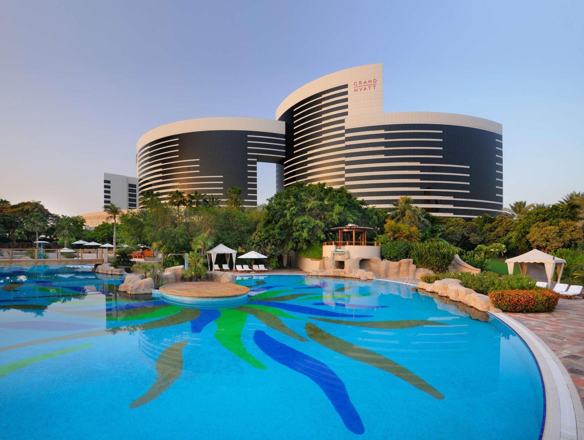 Grand Hyatt Dubai Hotel Ngoại thất bức ảnh The photo shows a modern architectural structure, likely a hotel or resort, characterized by two circular buildings with a sleek, contemporary design. The buildings are black and white with horizontal stripes and appear to have large windows. In the 